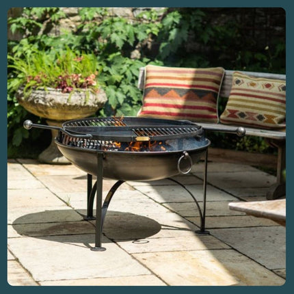 Fire pit with live fire and swinging cooking arm on a garden patio. 